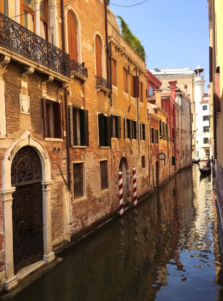 gondola navigating through the narrow canals along old colourful buildings in Venice Italy 