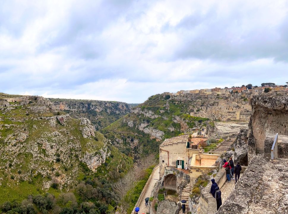 valley with one side matera town and on the other green rocky hills where old cave dwellings are still visible. 