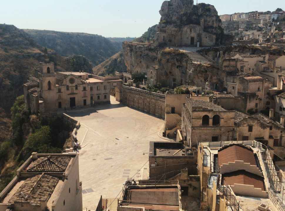 picture taken from a view point from where you can see an old cave church nearby a more new one. Hill landscape in the back in Matera