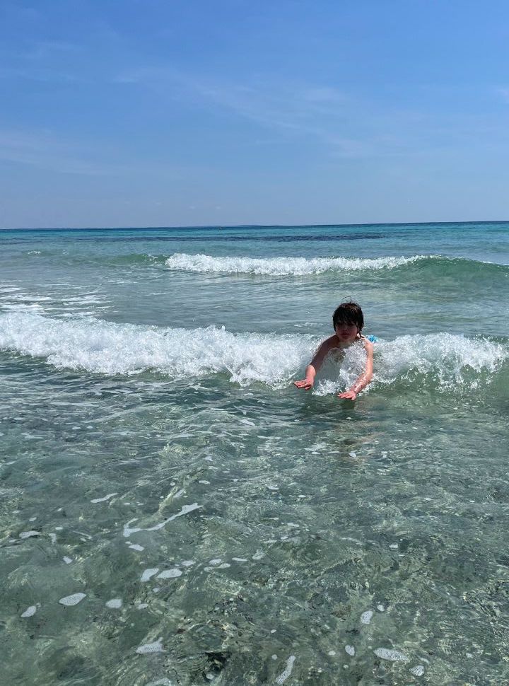 boy riding the waves at Punta Prosciutto in puglia
