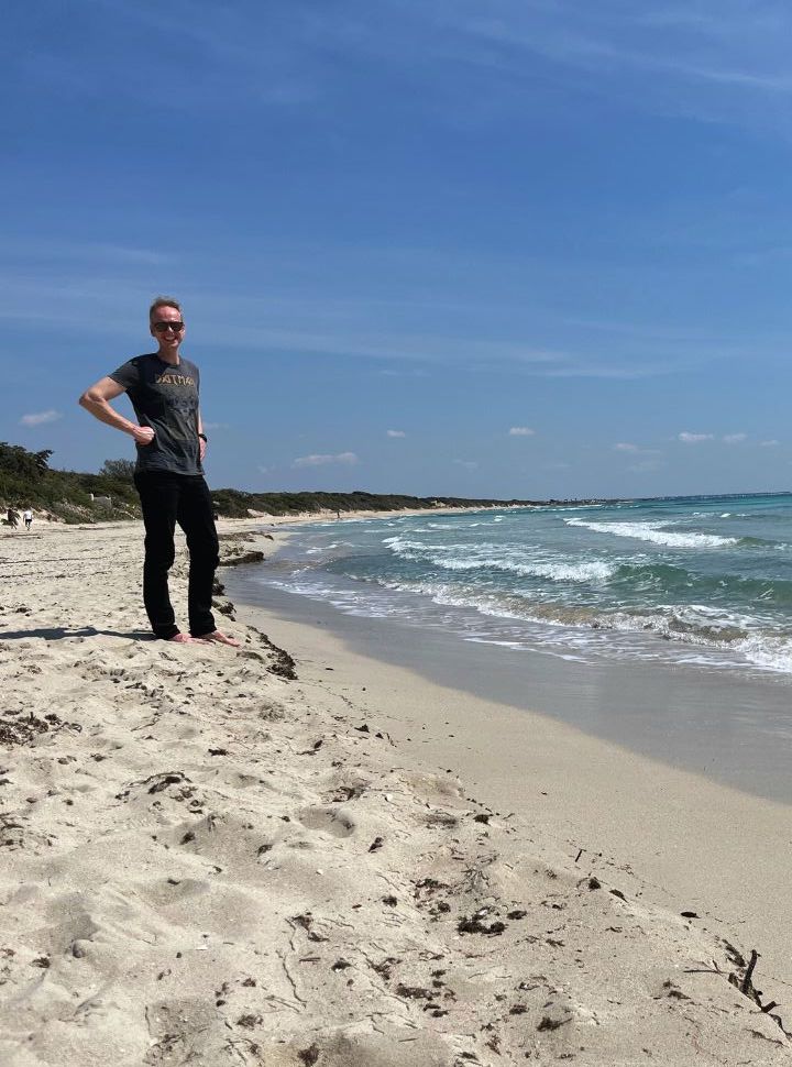 man posing at a soft sanded beach in puglia with dunes in the back