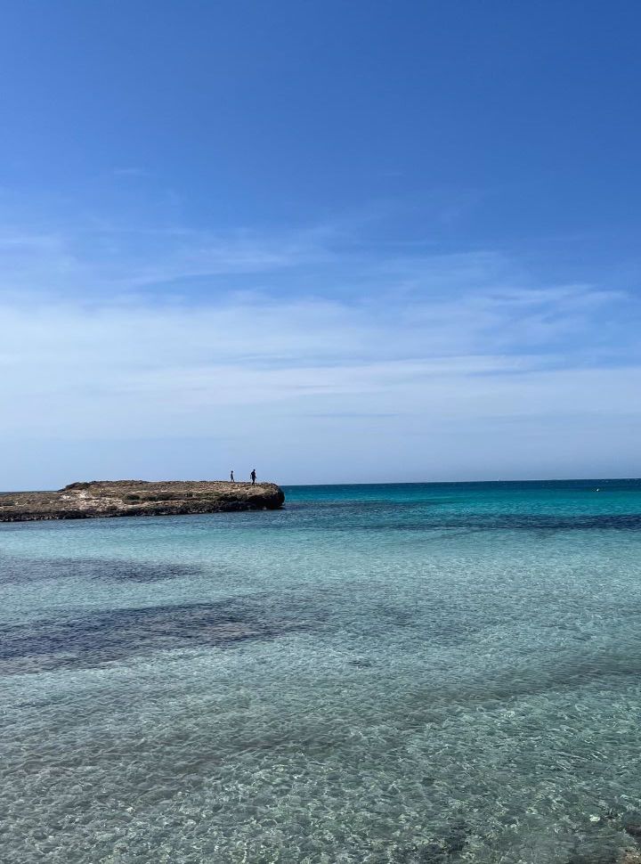 father and son walking on a rock formation far in to the ocean at Punta della suina Italy