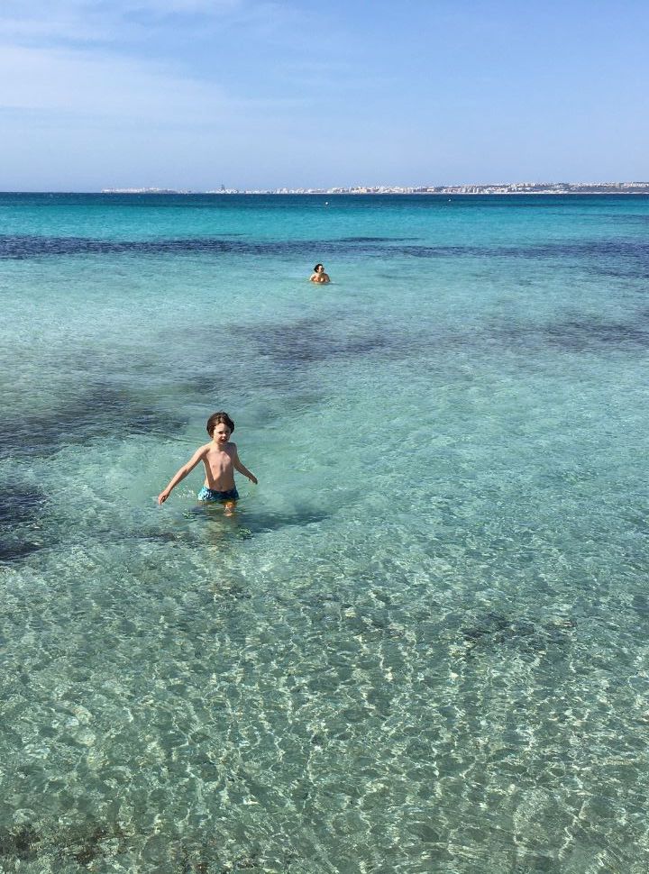 mother and son swimming in crystal water with different shades of blue at Punta della suina in Puglia