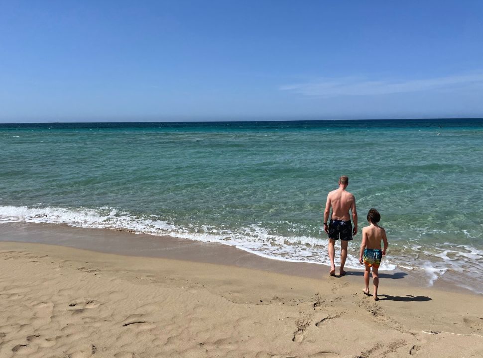 father and son ready to head in the ocean for a swim at Padula Bianca beach Puglia