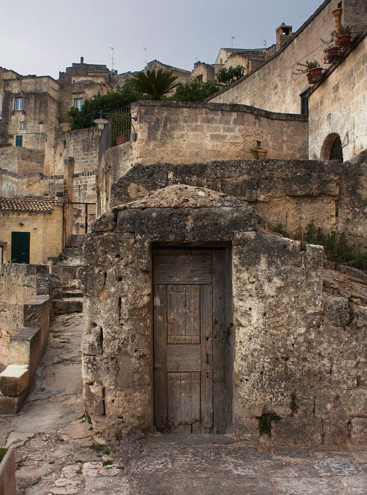 old door of a stone house, in the back there are better renovated houses in Matera Italy