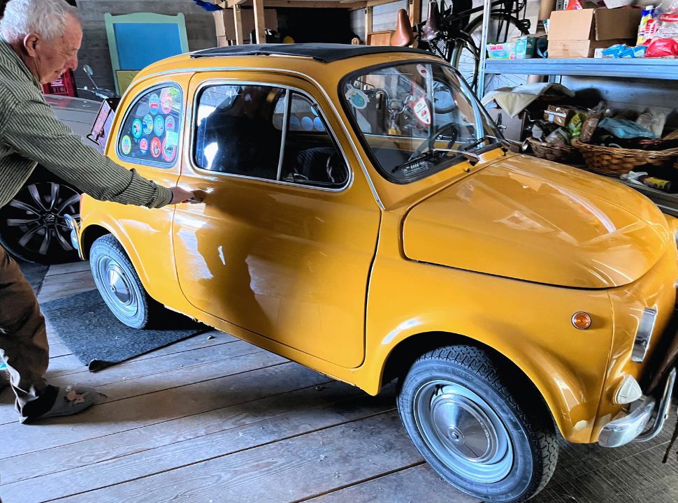 man opening a door to his fiat 500 car in the colour ochre standing in his garage