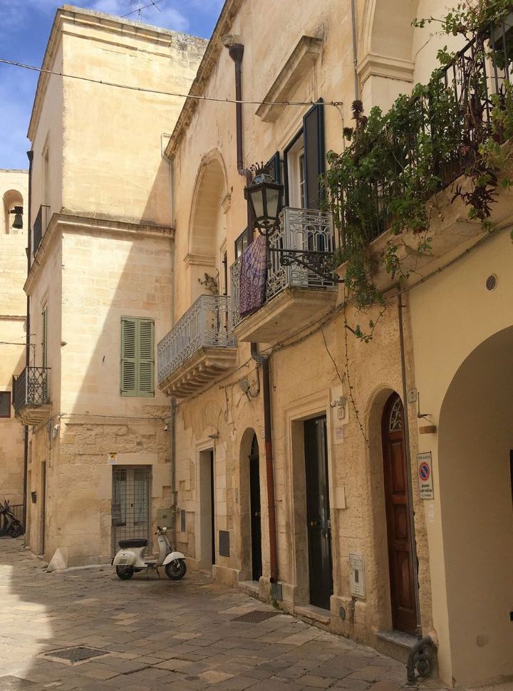 old characterful buildings with balcony with a classic vespa parked in front in Lecce puglia