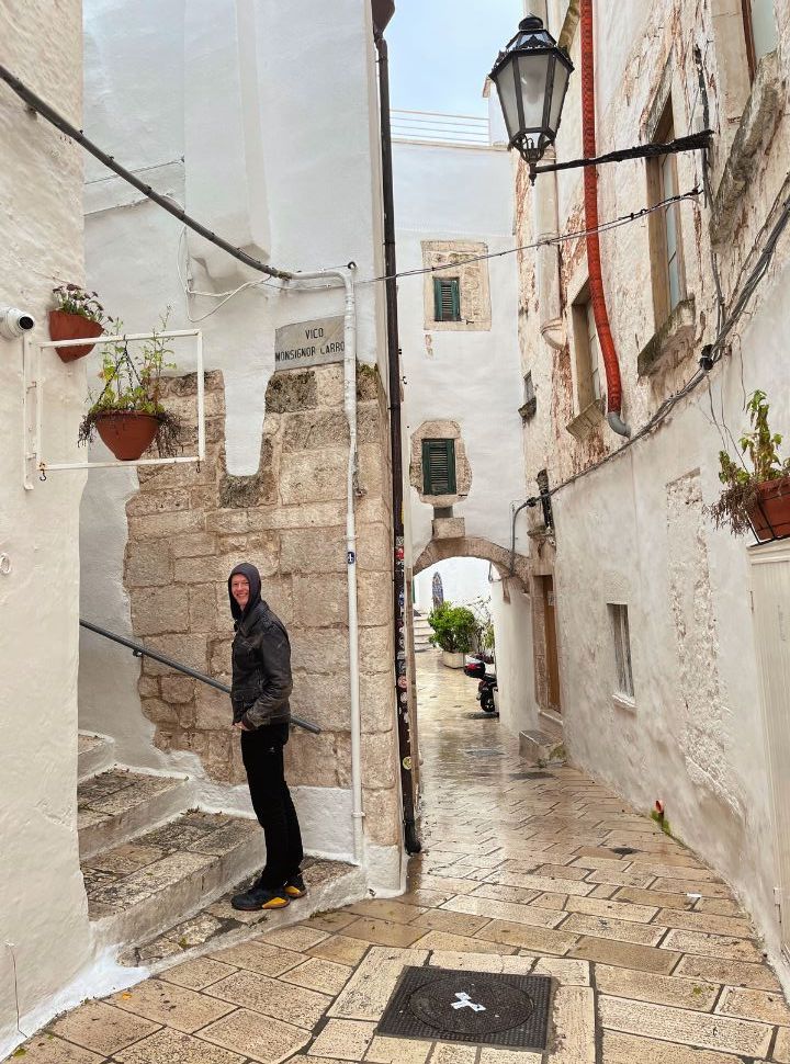 man climbing up the stairs within then narrow streets of Ostuni in the rain 