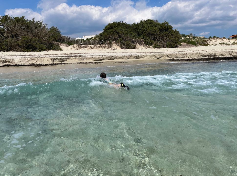 boy swimming in the waves at a deserted beach in Puglia Italy