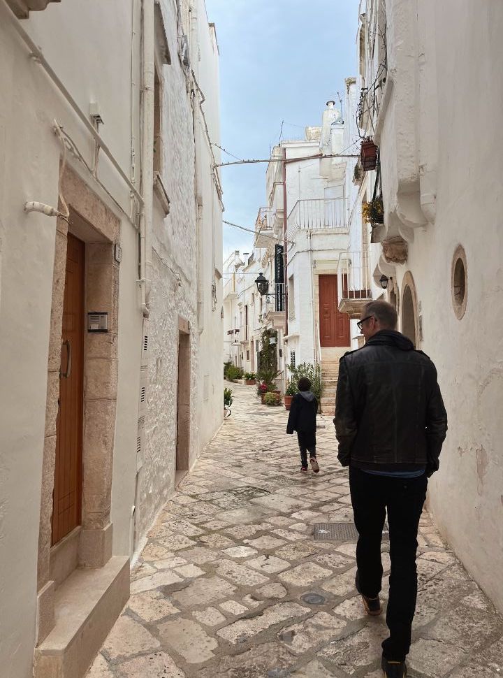 father and son walking through the narrow cobbled street with white housing in Locorotondo Puglia Italy