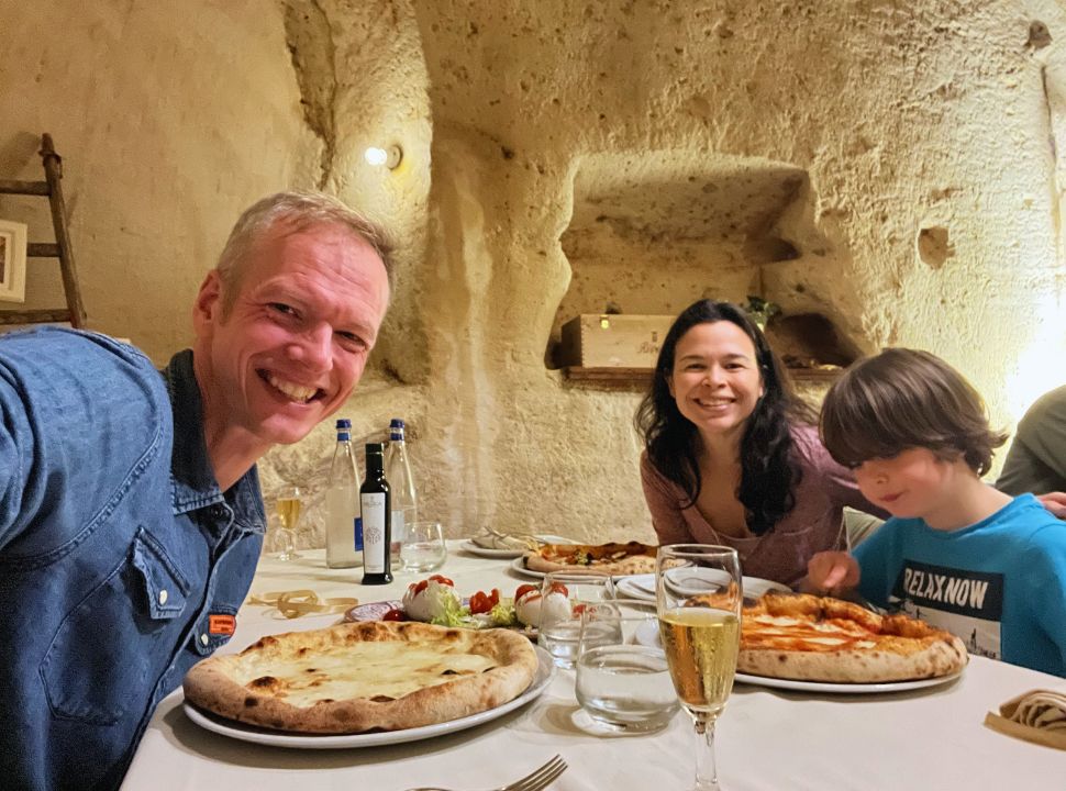 family of three having a pizza dinner in a cave restaurant in matera