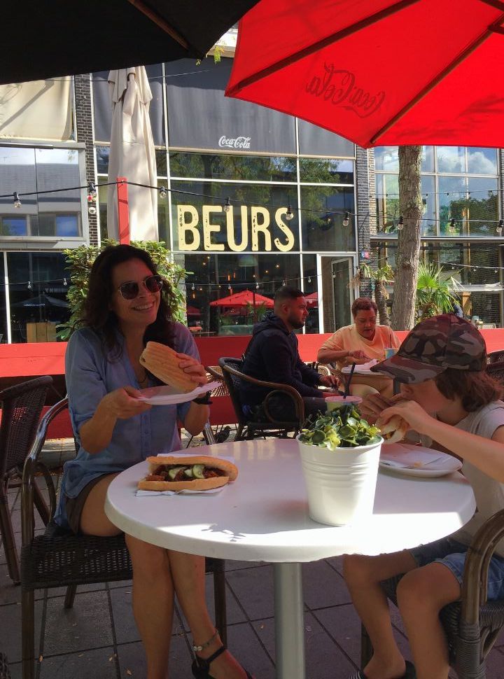 mother and son having a sandwich on a outdoor terrace under a red umbrella in Rotterdam