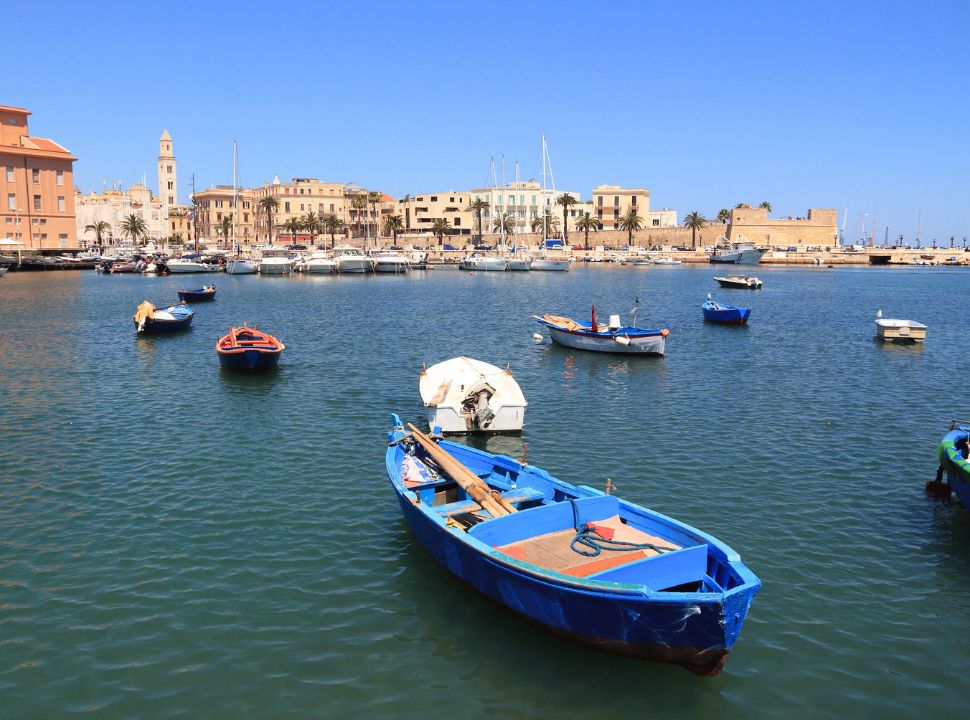 boats floating in front of Bari's waterfront, with the town skyline in the back. 