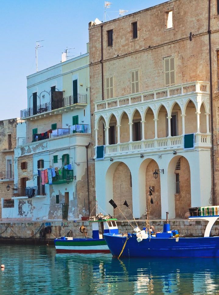 local fishing boats at the waterfront with a beautiful facade of an old building in Monopoli