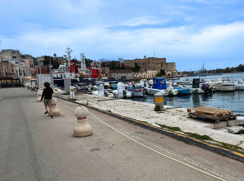 boy walking along the harbour of brindisi puglia