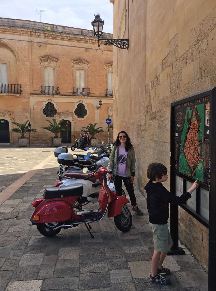 woman posing at a row of vespas in lecce puglia