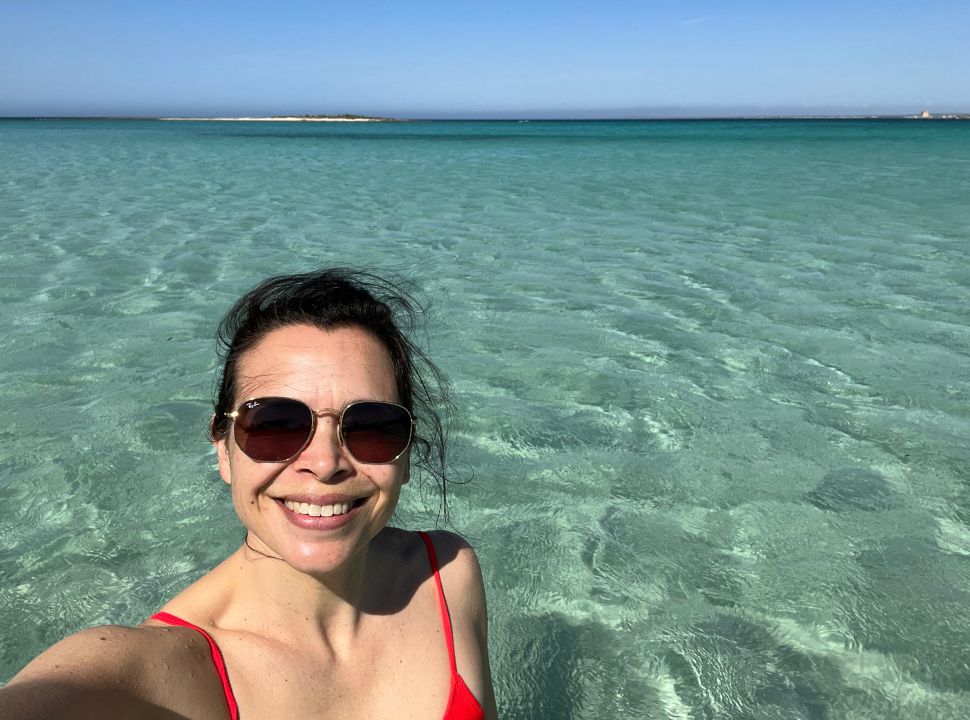 woman taking a selfie at a beach in Puglia with crystal clear water