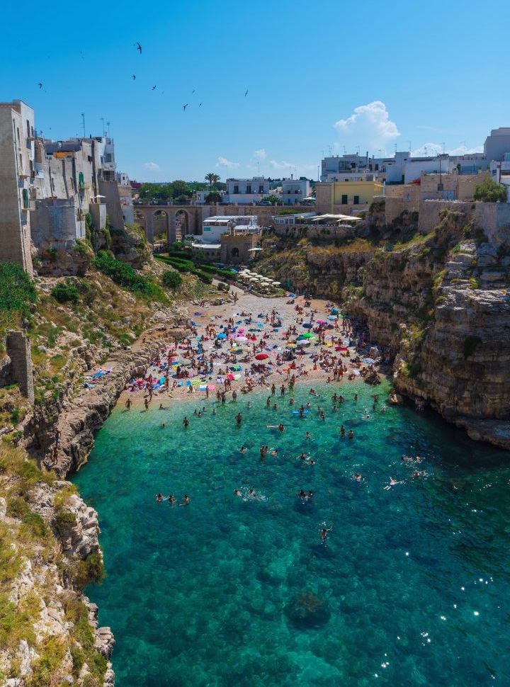 beach set within a cove in Polignano a Mare Puglia with a lot of people enjoying the sun and crystal clear water 