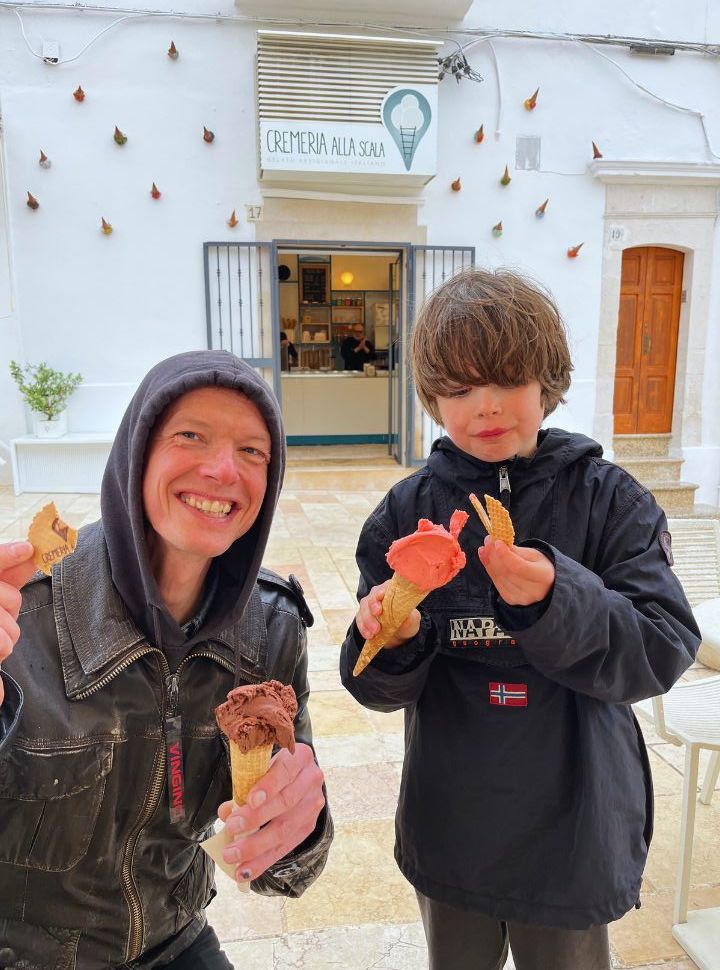 father and son enjoying italian ice cream in the rian in ostuni in the rain 