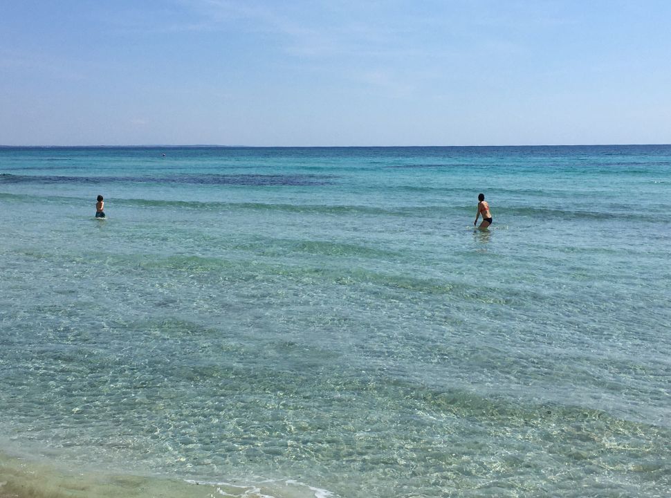 mother and son going for a swim in the clear ocean in puglia italy