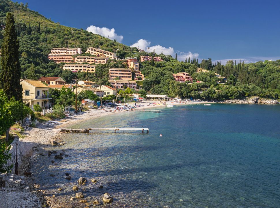 white sandy beach with accommodation located in the hills behind along the east coast of corfu