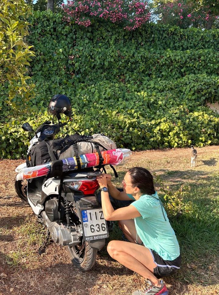 woman putting her luggage on her motorscooter in corfu greece