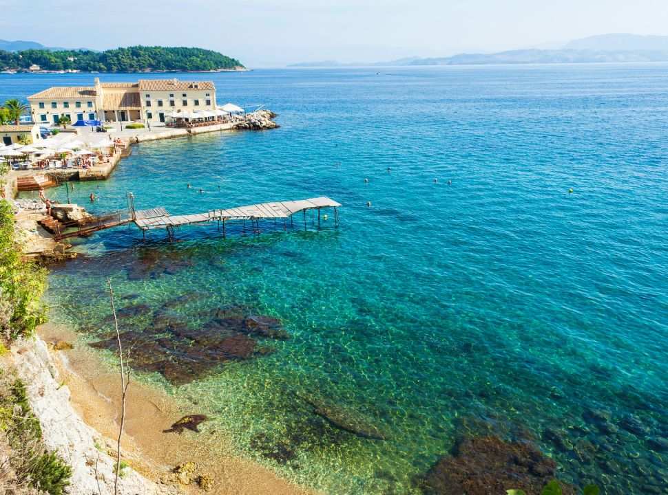 view of a beach with a pier and a terraces and a restaurant near the town of corfu