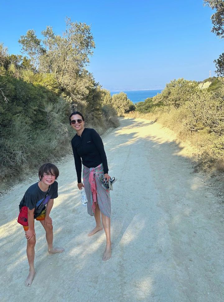 mother and son walking barefooted along a sandy dusty road in cape drastis area corfu