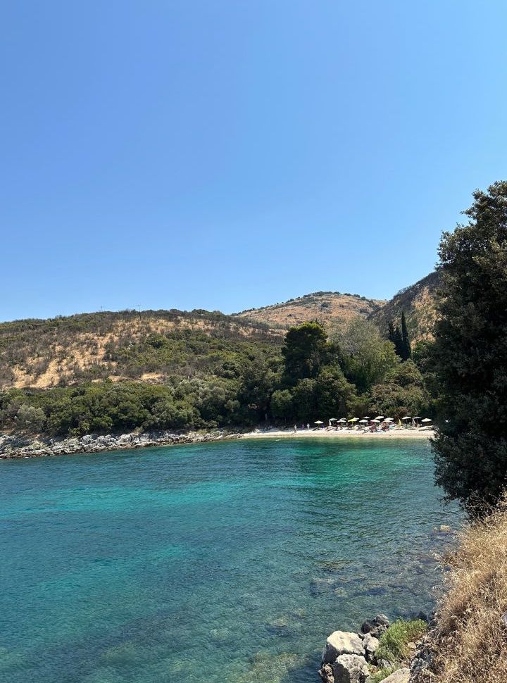 a small coved beach with sunglounger surrounded by hills and trees along the north coast of corfu