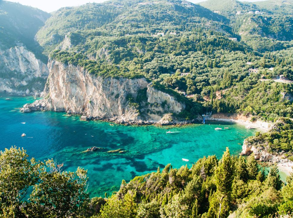 one of the many bays at paleokastritsa surrounded by hills covered with green vegetation