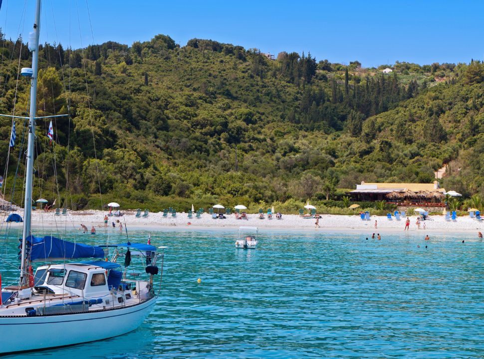 white sandy beach with green vegetations hills in the back, stunning blue water at antipaxos near paxos and corfu