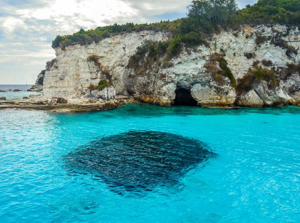 stunning blue water along caves and white cliffs near paxos greece