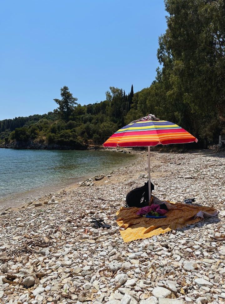 sun umbrella with belongings on a quiet pebbled beach in east corfu