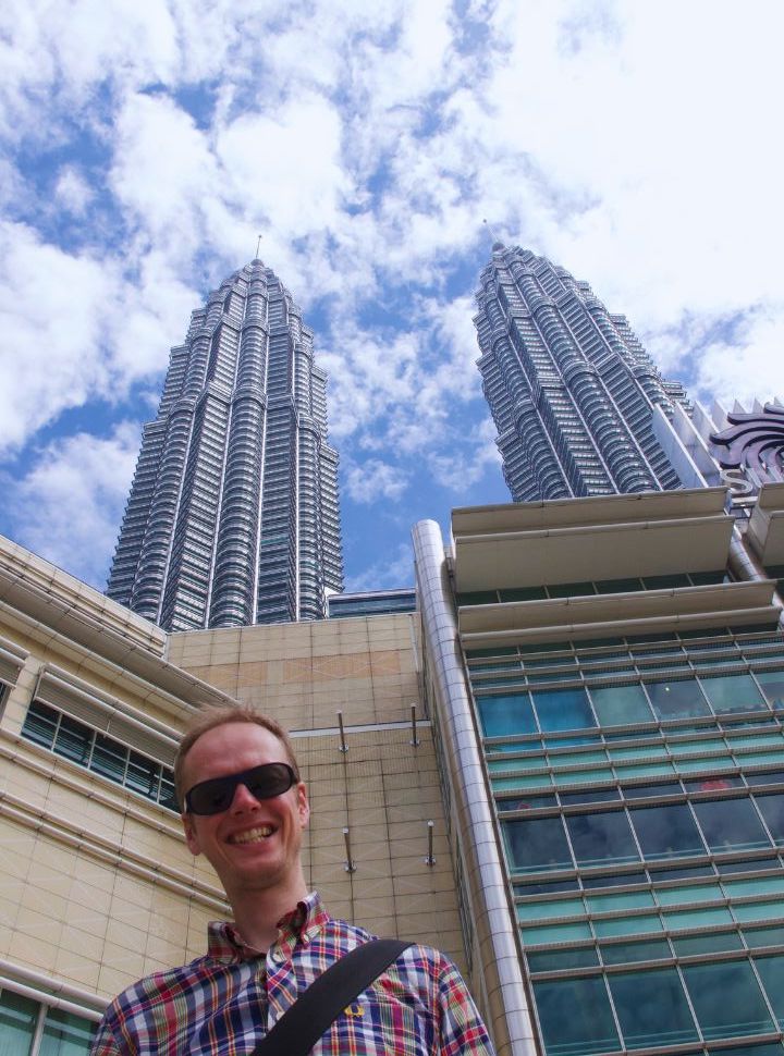 man posing in front of the petronas towers in kuala lumpur malaysia