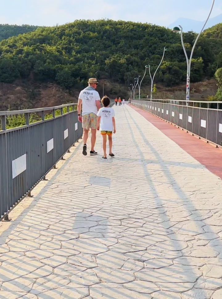 father and son walking on a paved path at Albania Blue Eye