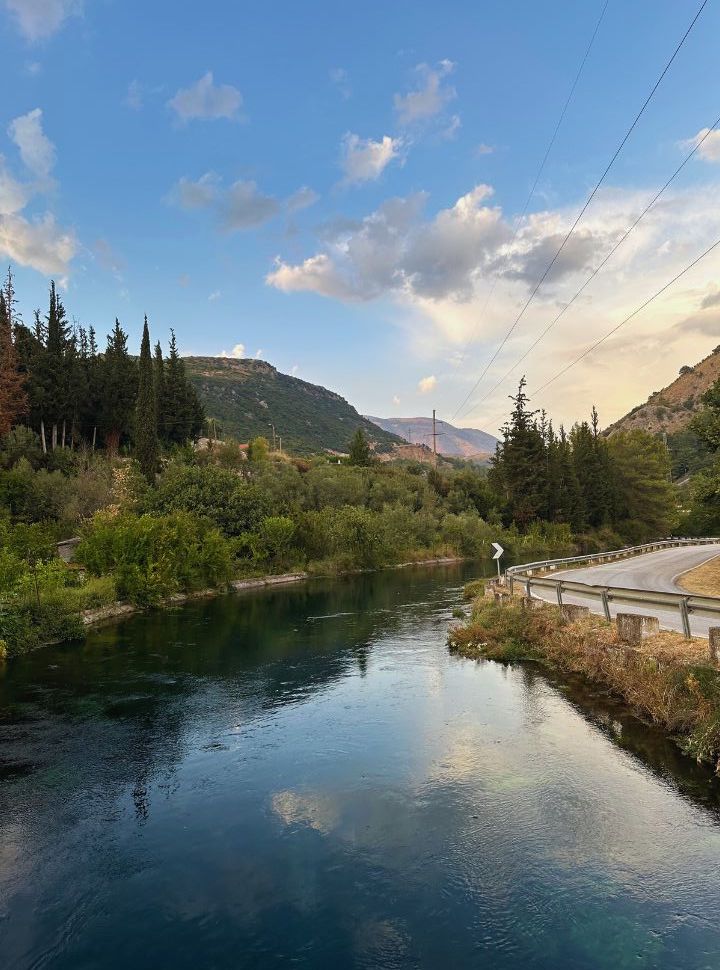 crystal clear river flowing  from the mountains, with one side the main road and on the other green vegetation in Mesopotam Albania