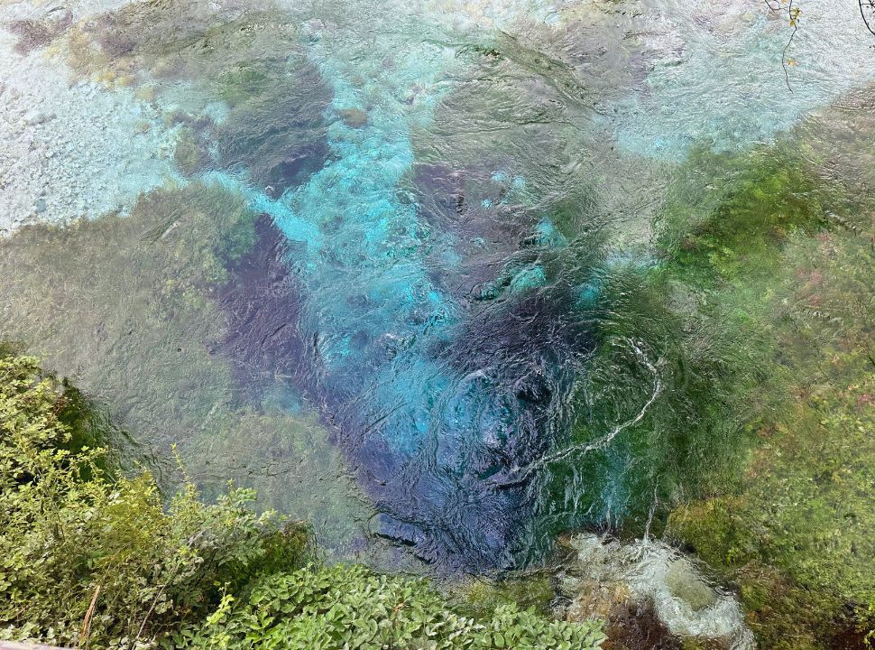 a natural spring with various shades of blue, the water is crystal clear as you can see rocks, and water plants at the blue eye Albania