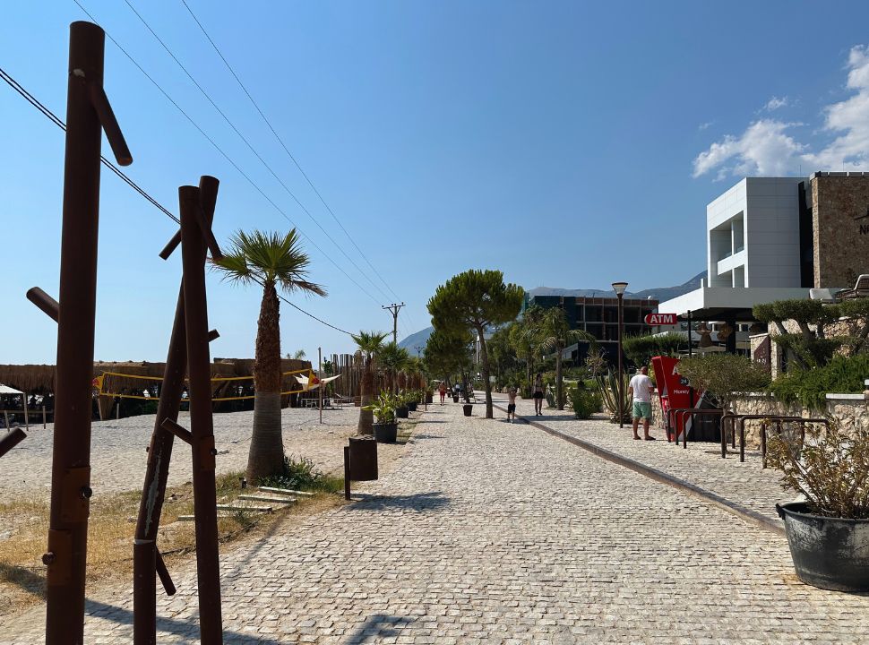 beach walk way with hotels on one side and the beach with beach club on the other at Dhermi Beach Albania