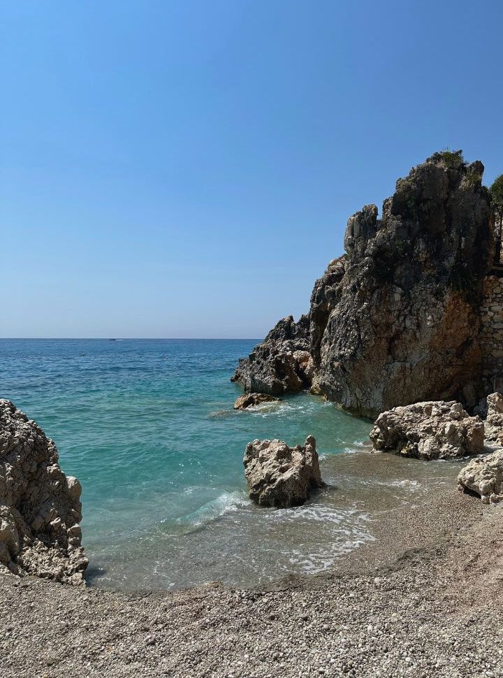 small patch of beach with a couple of sharp rocks with clear water at Dhermi beach Albania