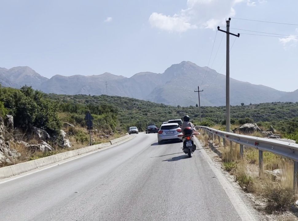 motorscooter driving along the cars on a well maintained road to Dhermi Albania