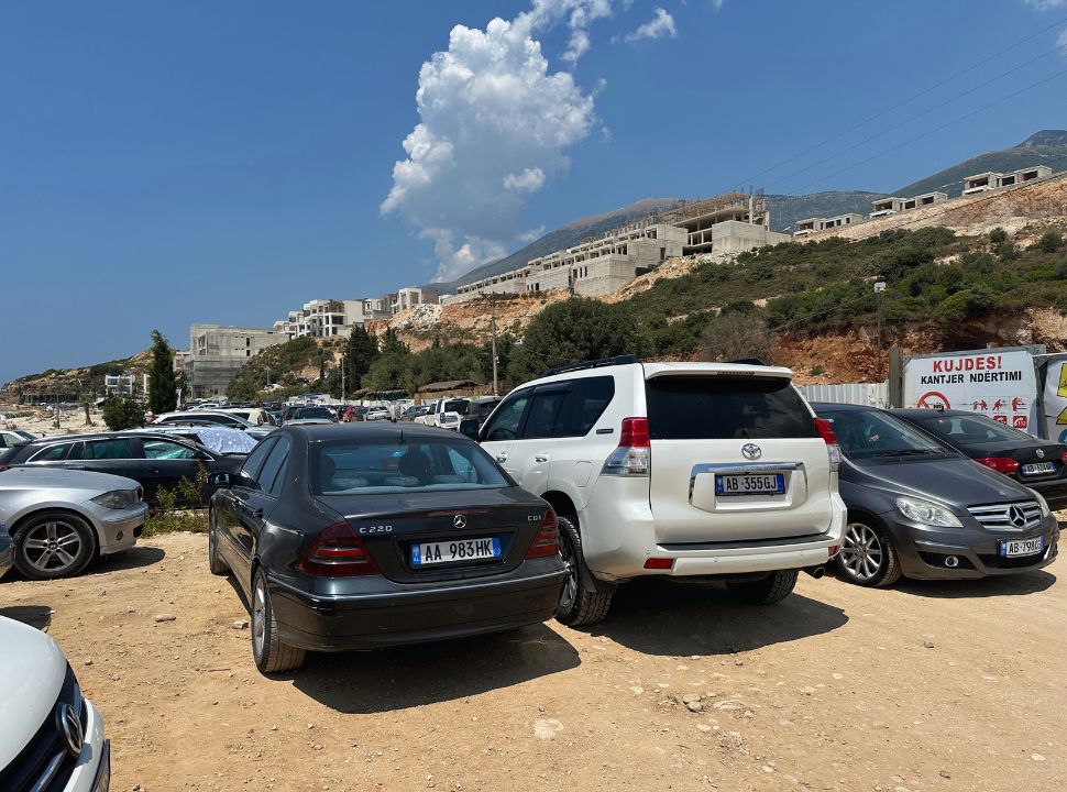 cars parked close to each other nearby a construction site where a resort is being built at Drymades beach Albania