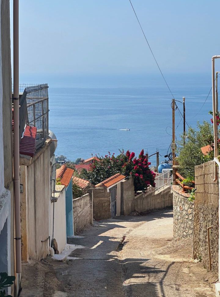 narrow alley going down hill, the ocean is visible in the back at Dhermi Beach Albania