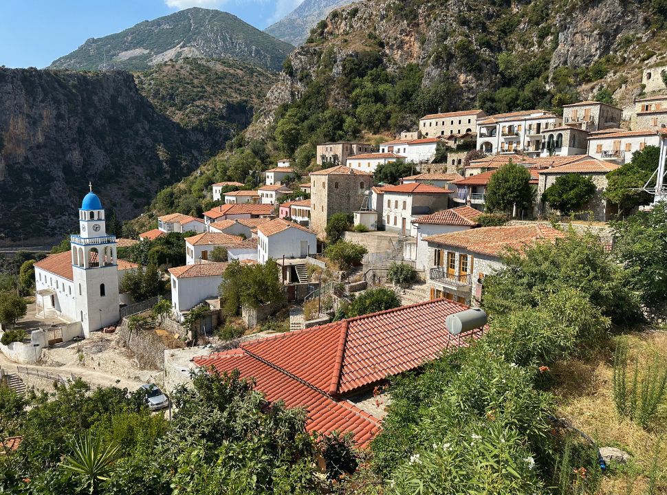 view of Dhermi Town with the blue bell tower of Spyridon Church and mountains in the back