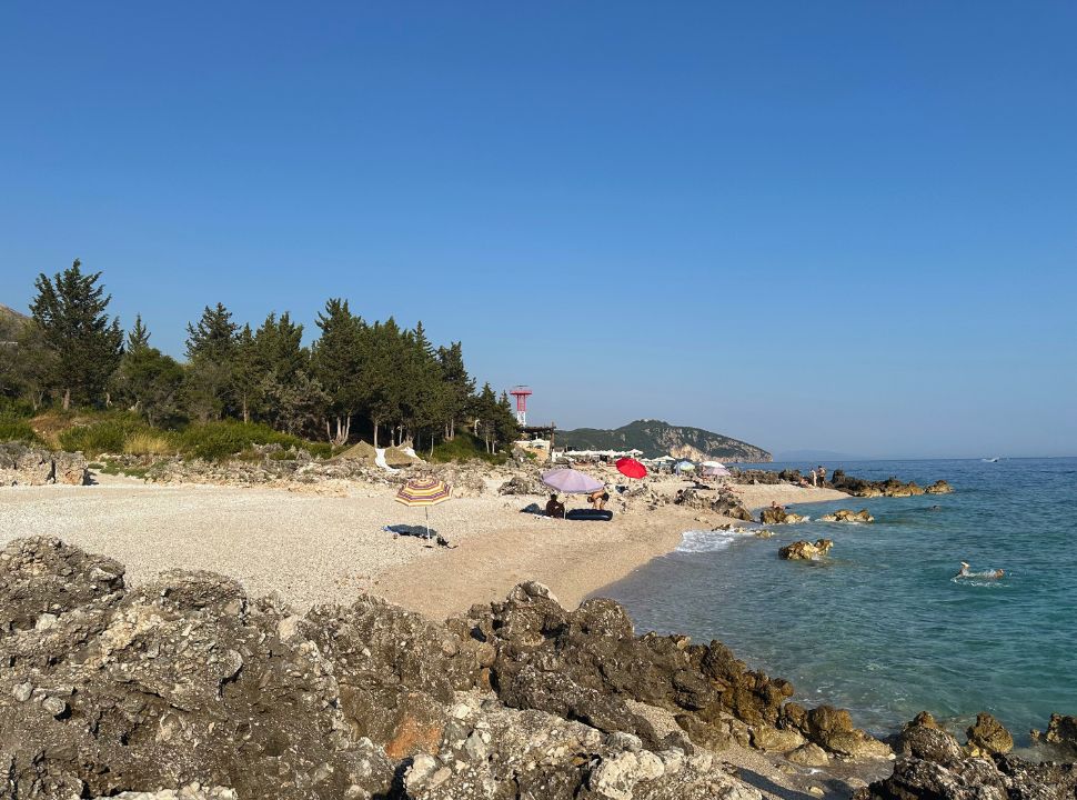 small beach with a couple of sun umbrellas near palasa beach Albania 