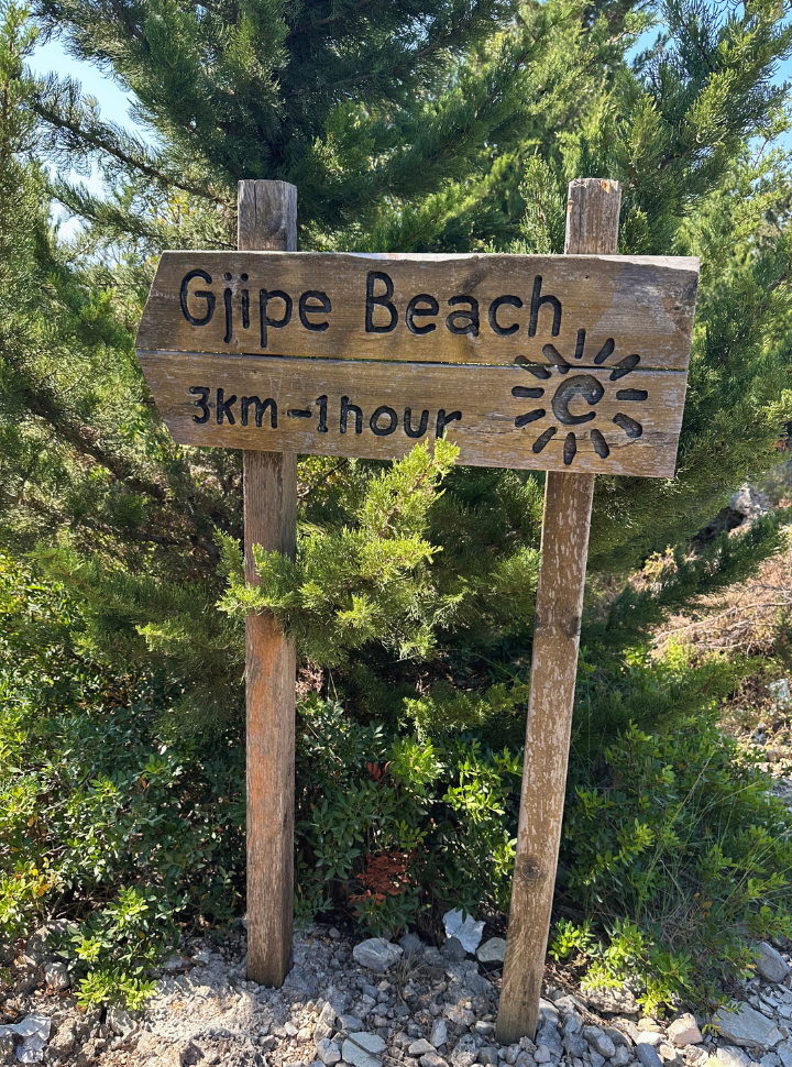 wooden sign pointing into the directions of the gjipe trail in Alabania