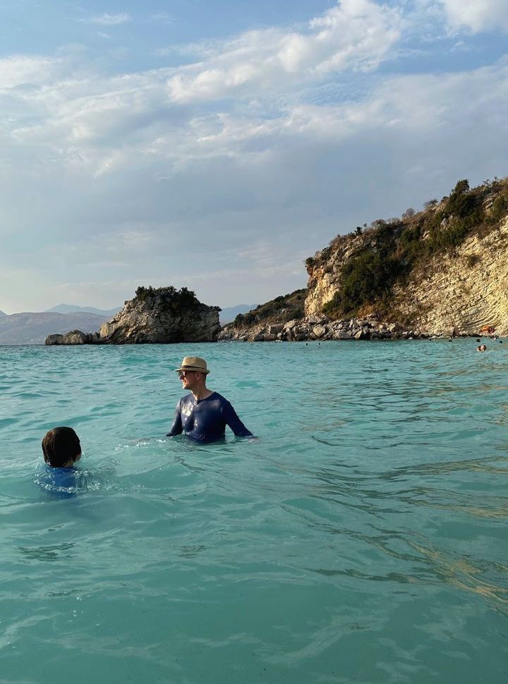 father and son swimming is a milky turquoise water in Albania