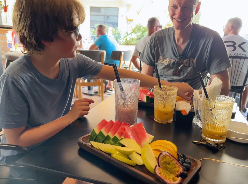 father and son having a fruit salad and juice at a restaurant in Ksamil