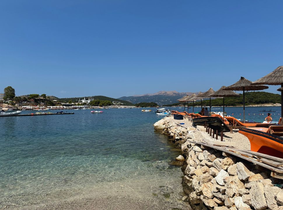 sun beds located on rocks overlooking the crystal clear ocean, in the distance you can see more beaches with sun beds in Ksamil