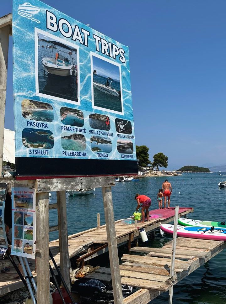 sign with a selection of boat trips offered at a beach in Ksamil