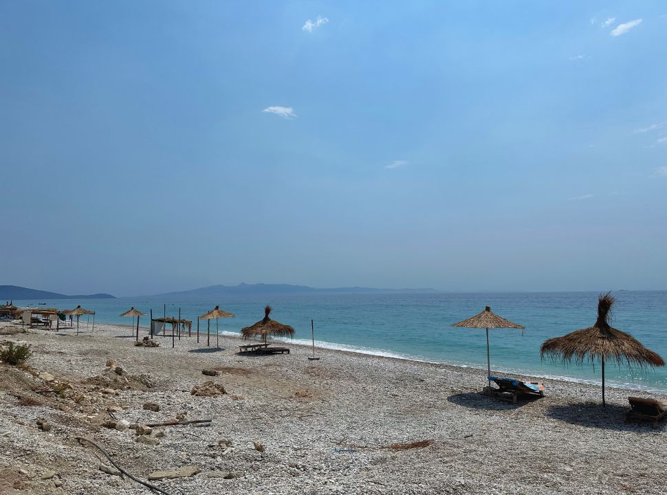 deserted thatched umbrellas that look like that it hasn't been used for a while, no body is using them and the beach is deserted along Borsh Beach Albania